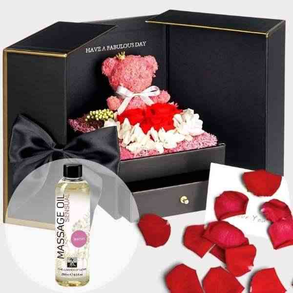 a teddy bear in a gift box with rose petals