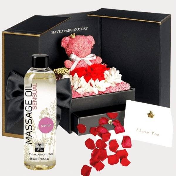 a teddy bear in a gift box with roses and a bottle of massage oil